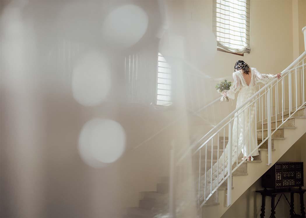 Una foto con aire onírico de la novia subiendo las escaleras con un vestido de larga cola