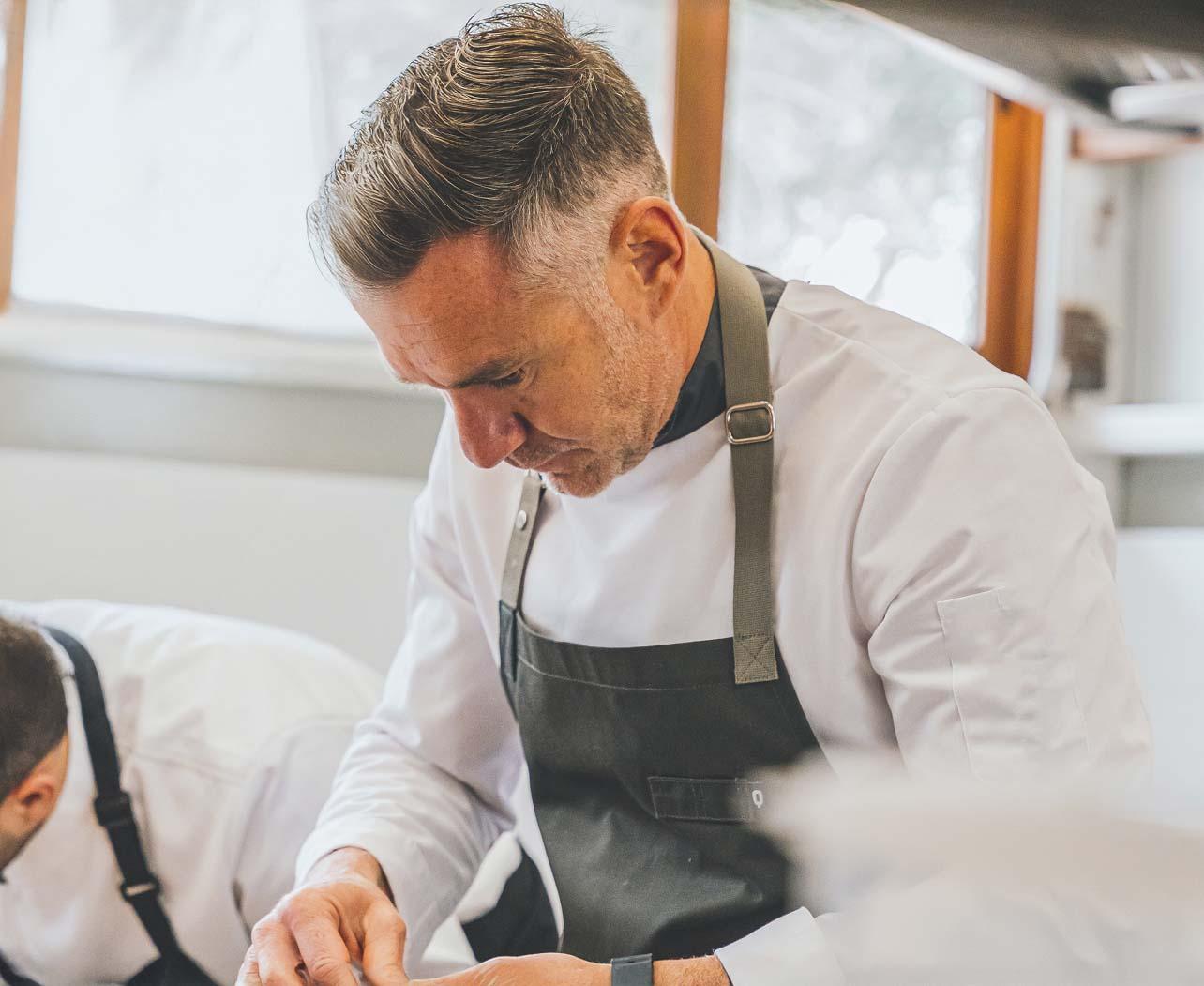 Nuestro chef rodeado de su equipo mientras cocina concentrado