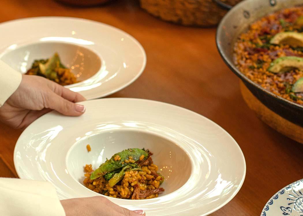 Unas manos posando un plato de arroz sobre la mesa