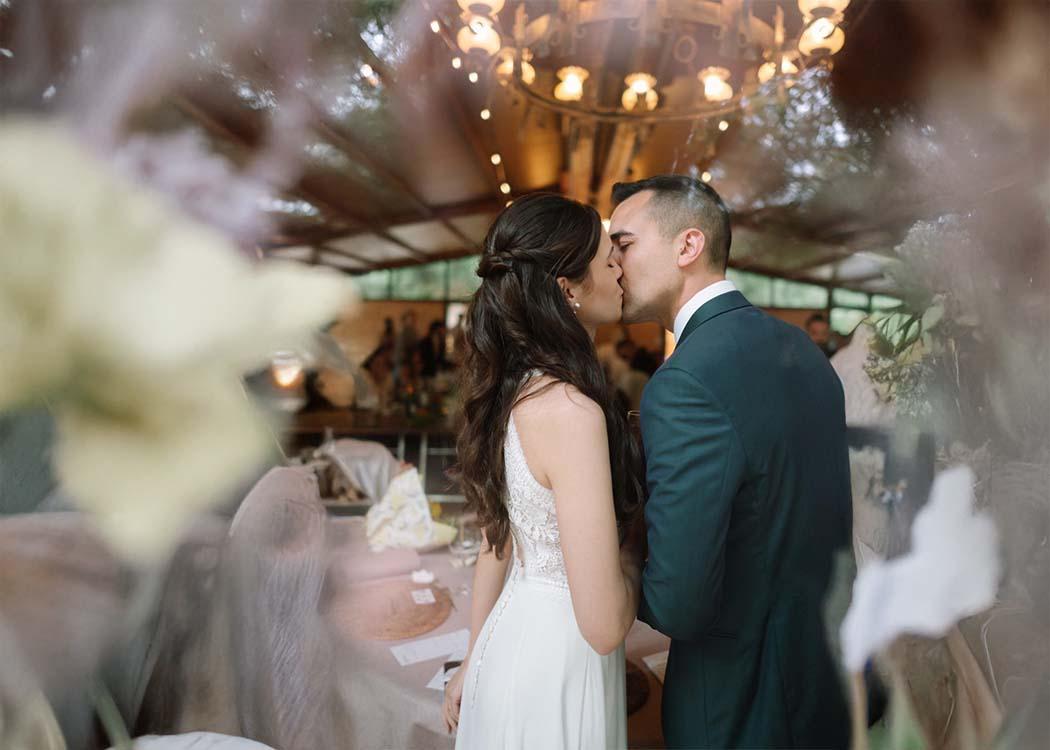 Dos novios se besan dentro de un salón de bodas