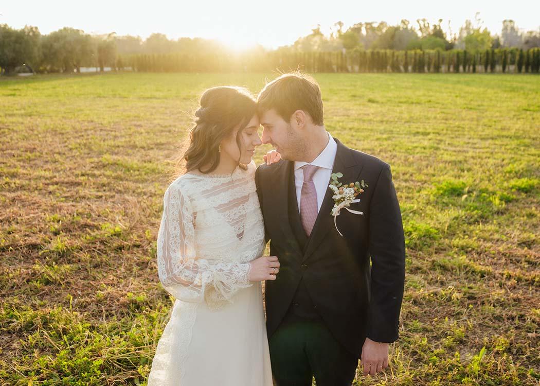 Una pareja de novios mirándose intensamente mientras el sol se pone tras suyo