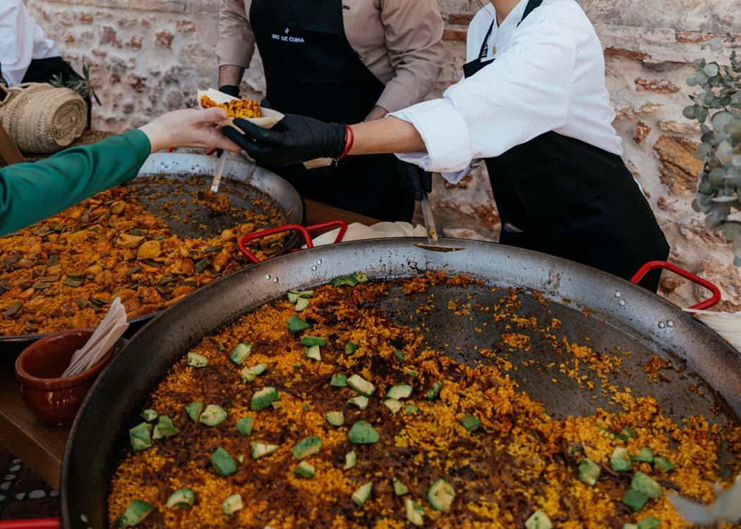 Miembros del equipo sirviendo paella a los invitados