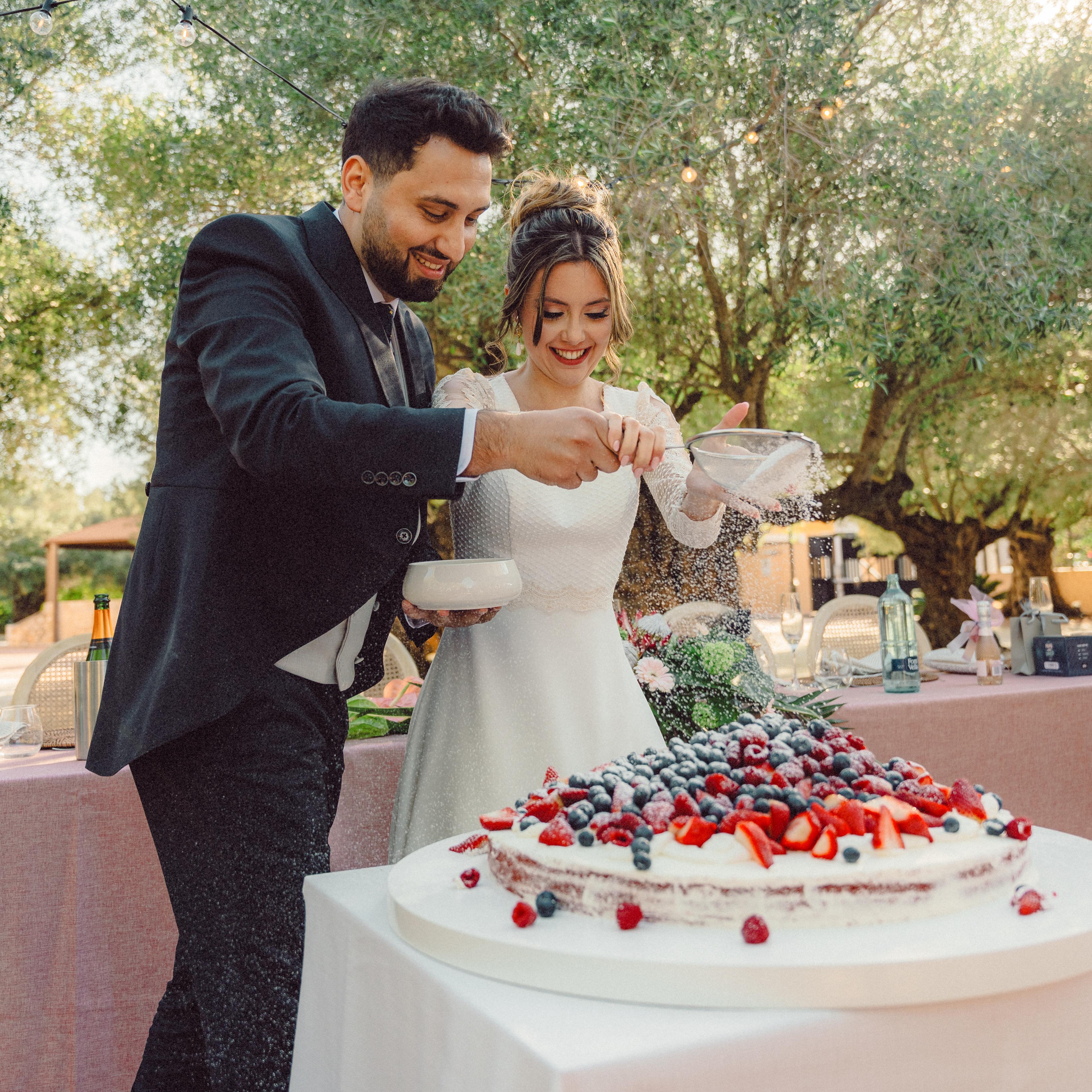 Una pareja divirtiéndose mientras decora su tarta nupcial