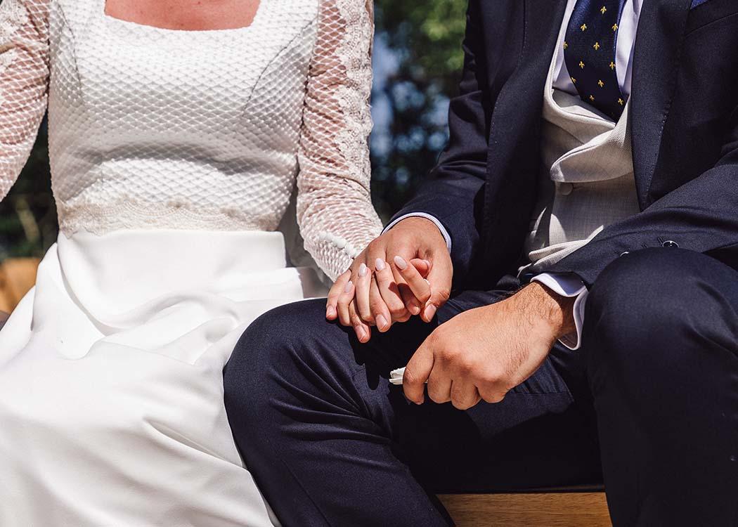 Un plano de detalle de dos novios cogiéndose la mano durante la ceremonia